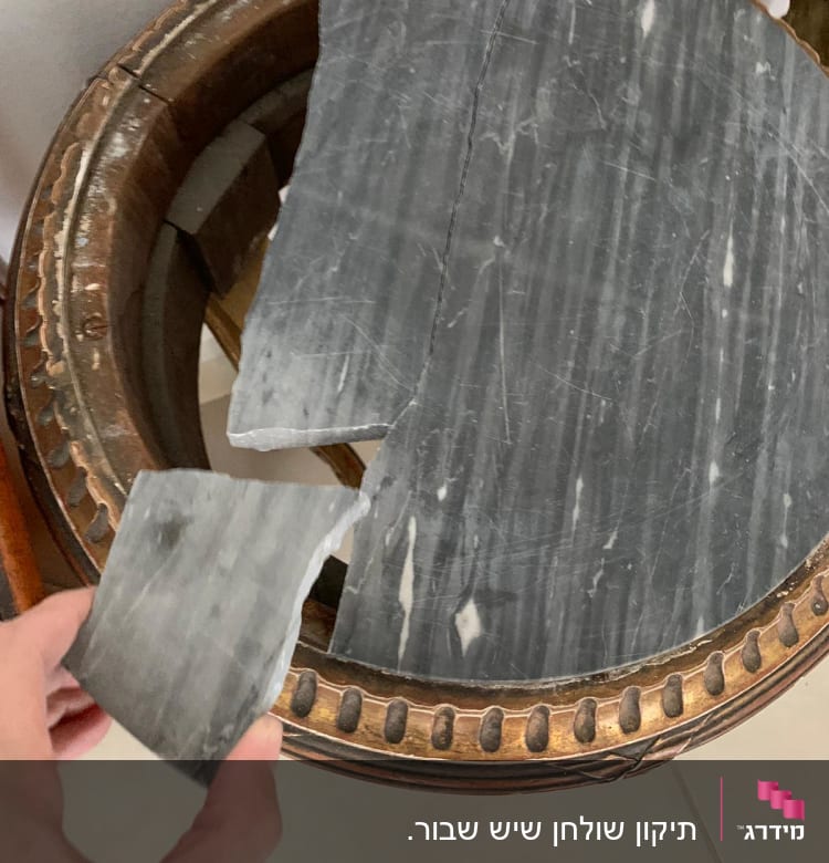 שבר שיש אפור ביד אדם על שולחן עץ